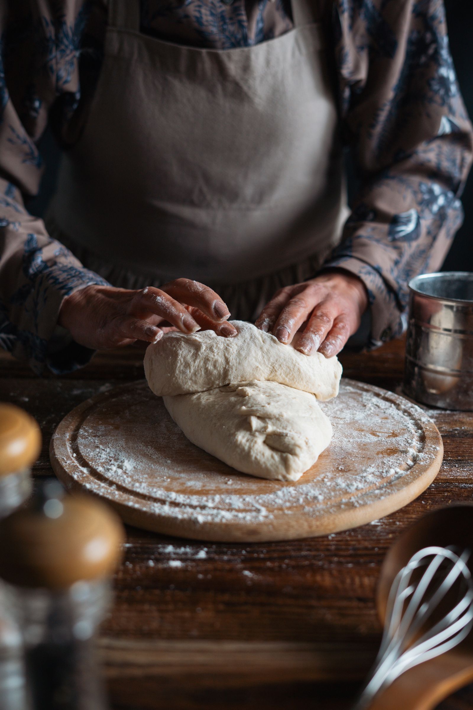 Hands working dough on a floured wooden table