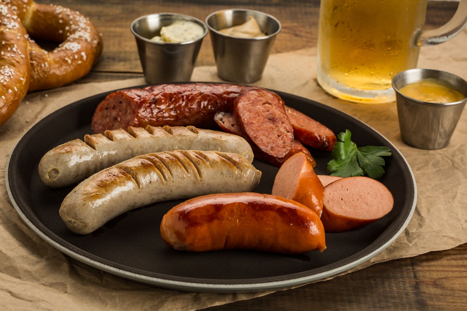 Grilled sausages with pretzel and beer on a wooden table