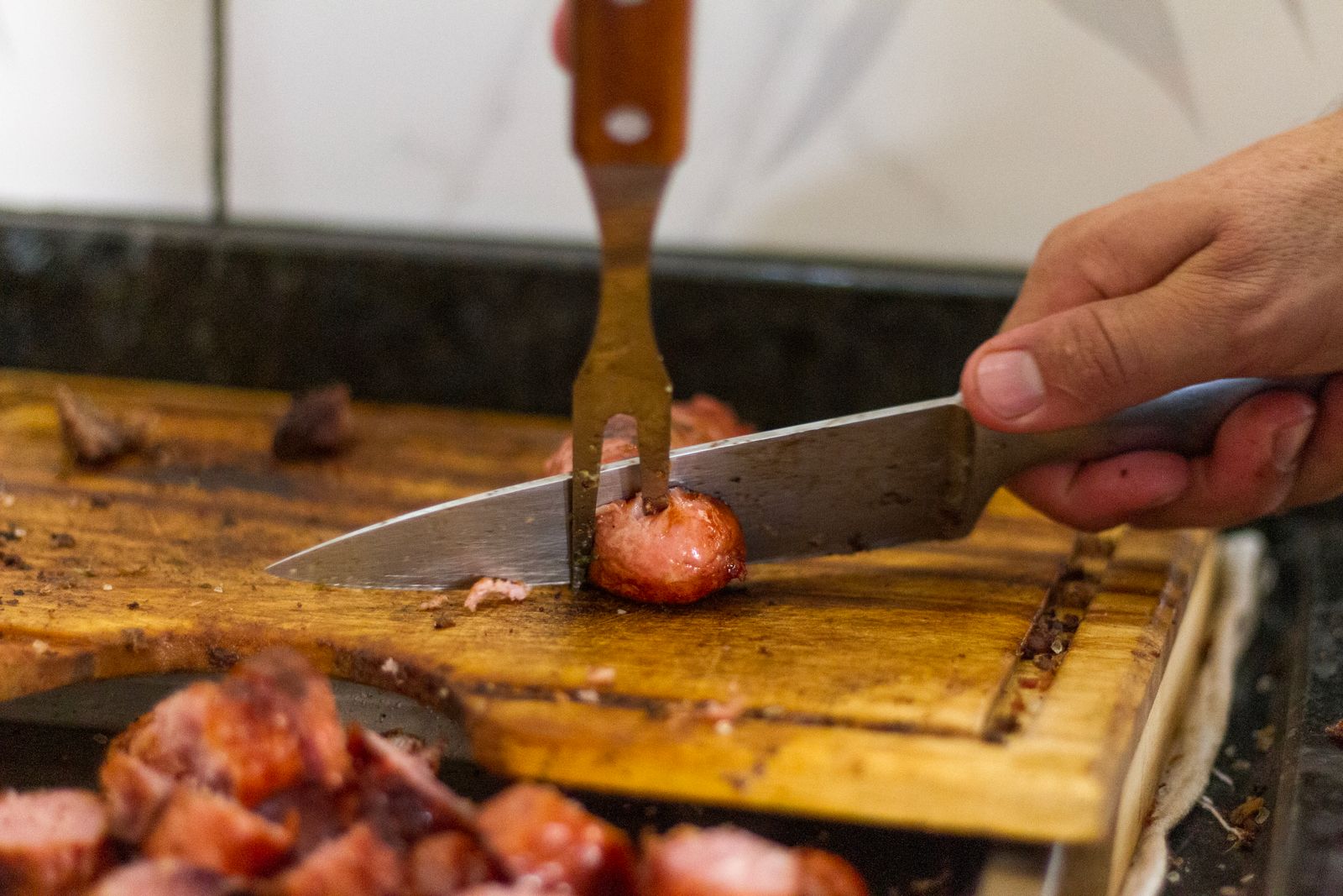 Slicing fresh sausage on a wooden board at Emil's